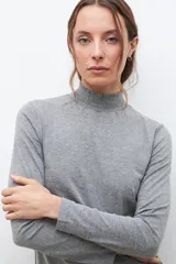 Remera gris melange de media polera con punto smock en el cuello y mangas largas.