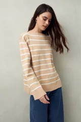 Sweater de punto color crema con rayas horizontales azul marino, cuello redondo y corte recto.