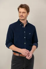Camisa de pana verde oscuro de corte clásico, con cuello button-down, cierre frontal de botones, bolsillo en el pecho con detalle bordado y mangas largas.