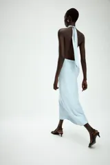 Vestido midi de satén color celeste, con cuello halter y detalle de lazada en la espalda descubierta.