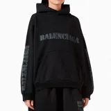 Hoodie Balenciaga de corte oversize, color negro con efecto desgastado. Presenta el logo de la marca estampado en estilo stencil en el pecho y en ambas mangas, con capucha y bolsillo frontal tipo canguro.