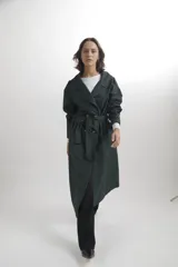 Trench largo de corte oversize en color azul marino, con solapas amplias, cierre frontal de doble botonadura y detalles de trabillas en los hombros y puños.