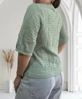 Blusa de manga corta color verde menta con cuello redondo y textura arrugada o plisada en toda la prenda.