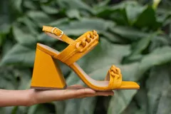 Sandalias de cuero celeste con puntera cuadrada, tira delantera con detalle de cadena y pulsera al tobillo con hebilla metálica. Tacón geométrico con detalle dorado.