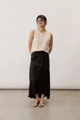 Falda larga de lino color beige, de corte asimétrico con costuras decorativas pespunteadas en contraste y diseño envolvente con bajo más largo en la parte trasera.