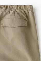 Pantalón relaxed fit en mezcla de algodón, de color beige, con cintura elástica ajustable mediante cordón, bragueta con botón y costuras decorativas giradas en las piernas.