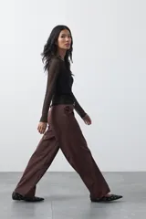 Pantalón wide leg color marrón chocolate, de tiro medio y corte relajado. Presenta detalle de hebillas laterales con ojales metálicos en la cintura y una caída fluida.