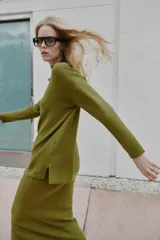 Jersey de punto liso color verde oliva, con cuello redondo, manga larga y aberturas laterales en el bajo.