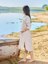 Vestido camisero largo color verde militar, confeccionado en lino, con cuello clásico, mangas largas con puños abotonados y cierre frontal con botones. Incluye un bolsillo de parche en el pecho.