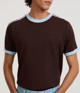 Remera de algodón color celeste con cuello redondo y bordes de mangas en color blanco. Presenta diseño de rayas dobles blancas en los hombros y mangas.