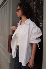 Camisa blanca de lino con cuello clásico, mangas abullonadas 3/4 y cierre frontal con botones.