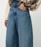 Pantalón barrel de jeans de tiro medio, con piernas amplias y afuniladas en el ruedo. Posee bolsillos funcionales, trabillas y cierre delantero con botón y cremallera.