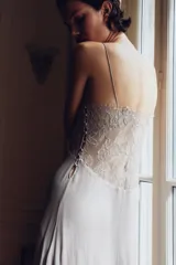 Vestido largo de viscosa con escote en pico, aplicación de encaje a tono en el busto, tirantes finos y diseño drapeado. Cuenta con forro interior y cierre lateral con botones forrados.