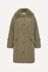 Parka color crema de corte recto, con cuello de piel sintética color beige, cierre frontal con botones a tono, bolsillos laterales con solapa y puños con trabilla ajustable.