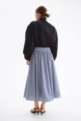 Pollera midi de corte acampanado, con diseño a rayas en azul marino y blanco. Presenta tiro alto y una amplia cintura elástica fruncida en punto smock.