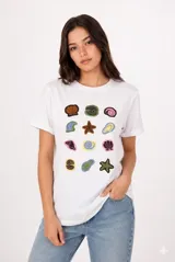 Remera de manga corta color beige, con cuello redondo y diseño al cuerpo. Presenta un estampado frontal multicolor de estilo veraniego con temática marina y detalles con glitter.
