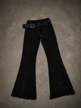 Pantalón de jean negro corte oxford, con costuras verticales deshilachadas y ruedo desflecado. Incluye un cinturón negro con tachas metálicas.