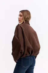 Campera de gamuza sintética color verde oliva, con silueta amplia, hombros caídos y cierre frontal. Presenta un diseño estructurado con volumen en mangas y cuerpo.