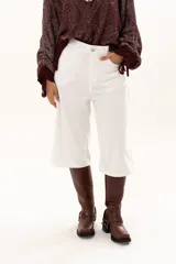 Bermuda de corte recto y tiro alto, confeccionada en gabardina blanca, con cierre frontal de botón y cremallera, y bolsillos laterales.