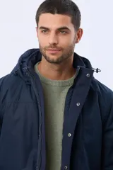 Campera de abrigo color azul marino, con capucha desmontable, cierre frontal con solapa, bolsillos frontales con solapa y detalle de etiqueta de cuero sintético. Cuenta con interior forrado en corderito en la parte superior para mayor calidez.
