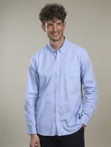 Camisa celeste de manga larga con cuello abotonado y bolsillo en el pecho.