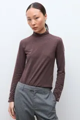 Media polera de manga larga con cuello alto y detalle de frunces en los puños, confeccionada en tejido suave y elástico.