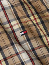 Camisa de hombre Tommy Hilfiger de algodón orgánico, con diseño de cuadros en tonos beige, blanco, amarillo y rojo. Tiene cuello abotonado, mangas largas y logo bordado en el pecho.