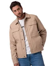 Chaqueta de canvas color beige con forro interior de franela. Presenta cierre frontal con botones metálicos, bolsillos en el pecho con solapa y bolsillos laterales. Incluye etiqueta de marca en el bolsillo inferior.