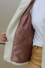 Campera de paño de lana en color beige jaspeado, con diseño oversize. Presenta detalles en pana color marrón chocolate en los puños y en las tapas de los bolsillos frontales. Cuenta con cierre frontal de botones grandes y cuello alto.