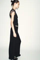 Top de manga caída, con efecto de doble capa. La capa exterior es negra y ajustada, mientras que la capa interior, visible en mangas y cuello, es de color marrón topo.