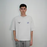 Remera blanca de algodón con estampado en la espalda que incluye una estrella plateada, la palabra "Venefo" en azul y una frase en letras azules más pequeñas.