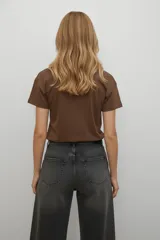 Remera de algodón negra de manga corta con cuello redondo. Presenta un estampado frontal abstracto compuesto por líneas verticales en tonos azules y detalles de lentejuelas plateadas, acompañado por el texto 'ABSTRACT MOTION'.
