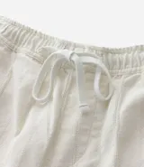 Bermuda recta de playa en color blanco roto, confeccionada en algodón texturizado con efecto de rayas verticales. Posee cintura elástica con cordón ajustable.