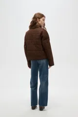 Campera acolchada de algodón con estampado animal print de leopardo en tonos marrones. Presenta cuello alto, cierre frontal, mangas largas y dos bolsillos frontales con ribetes oscuros.