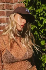 Gorra marrón de algodón con logo bordado en celeste en el frente y ganchito ajustable en la parte trasera.