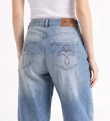 Jeans de corte barrel relajado, confeccionado en denim celeste claro con pespuntes y atraques a contratono en bordó. Presenta tiro medio, diseño de pierna curva y bolsillos traseros con logo bordado.