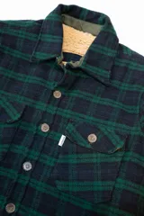 Campera de tartán grueso forrada con corderito marrón, con cuello camisero, cierre con botones, dos bolsillos frontales en el pecho y dos bolsillos para las manos.