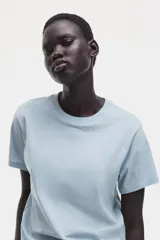 Remera de corte recto y suave tejido de punto de algodón, color celeste, con cuello redondo ribeteado y hombros ligeramente caídos.