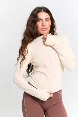 Campera deportiva de ajuste entallado, color crudo, con cuello alto, cierre frontal completo y mangas largas con orificio para el pulgar.