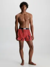 Boxer de algodón con estampado repetido del logo 'CK' en negro sobre fondo rojo. Cintura elástica negra con el logo 'Calvin Klein' en blanco.