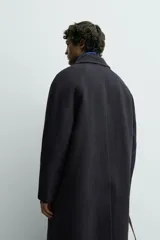 Abrigo de corte relajado confeccionado en tejido con lana. Presenta cuello solapa, cierre frontal con botones, mangas largas y bolsillos de vivo en la cadera. Incluye una abertura en el centro de la espalda.