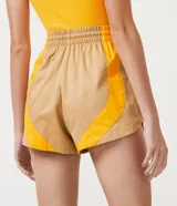 Short runner color beige con recortes laterales color naranja, cintura elástica con cordón ajustable y corte holgado.