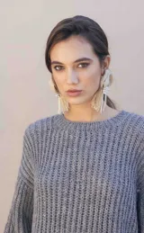 Buzo de tejido grueso con textura marcada, corte relajado y levemente corto, con cuello redondo y mangas largas amplias.