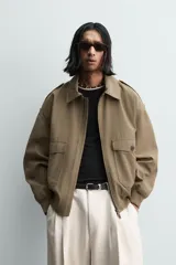 Cazadora de corte cropped fit, color verde oliva, confeccionada en mezcla de viscosa y algodón. Presenta cuello subido, manga larga, trabillas en los hombros, bolsillos de plastrón con solapa en la cadera y cierre frontal con cremallera.