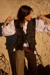 Chaleco de tweed con diseño estructurado y volados decorativos en lino. Presenta un cierre frontal con cintas para atar y un corte entallado.