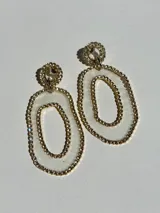 Aros colgantes con diseño de doble óvalo, compuestos por una pieza circular superior y una pieza ovalada inferior, ambas con borde de strass y centro transparente.