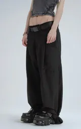Pantalón negro de corte ancho y tiro alto, con múltiples bolsillos cargo y ajuste en los tobillos. Se lleva con un cinturón negro con hebilla metálica.
