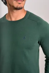 Sweater de punto fino color verde oscuro, con cuello redondo y mangas largas con puños acanalados. Presenta un pequeño logo bordado en el pecho.