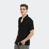 Camisa negra de manga corta con cuello clásico y cierre frontal con botones. Diseño liso y corte regular.