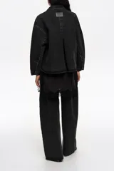 Chaqueta corta de corte línea A confeccionada en mezcla de algodón color negro. Presenta cuello camisero, mangas largas con botones, bolsillos delanteros tipo plastrón y canesú con maxi pliegue en la espalda.